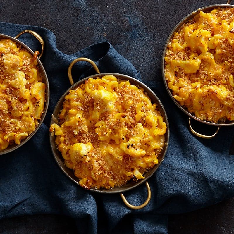 Three individual servings of cheesy cauliflower-macaroni and cheese, topped with crispy panko breadcrumbs